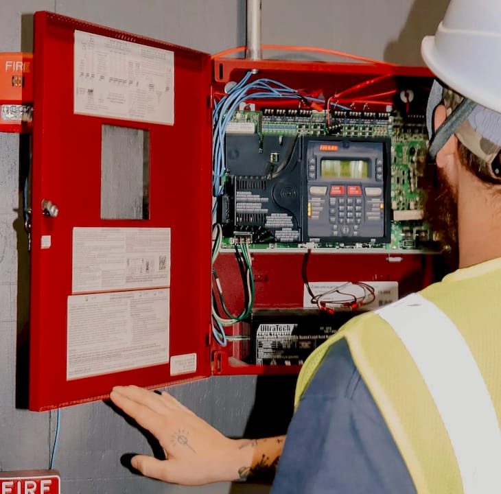 Engineer inspecting fire alarm control panel