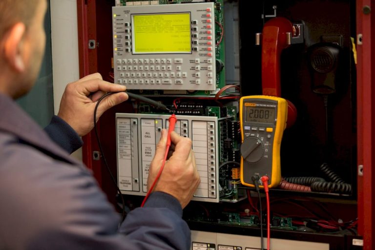 Fire alarm technician inspecting panel in utility room
