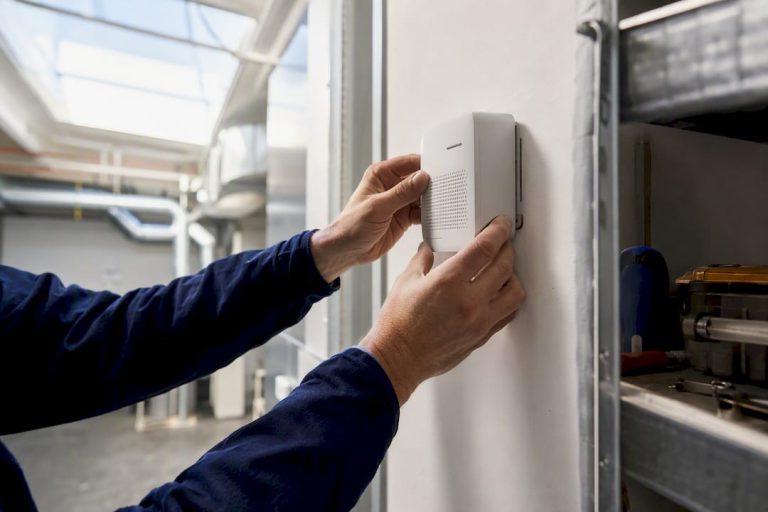 Hands adjusting air quality sensor indoors
